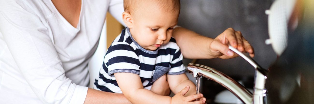 a woman and baby washing hands at a sink