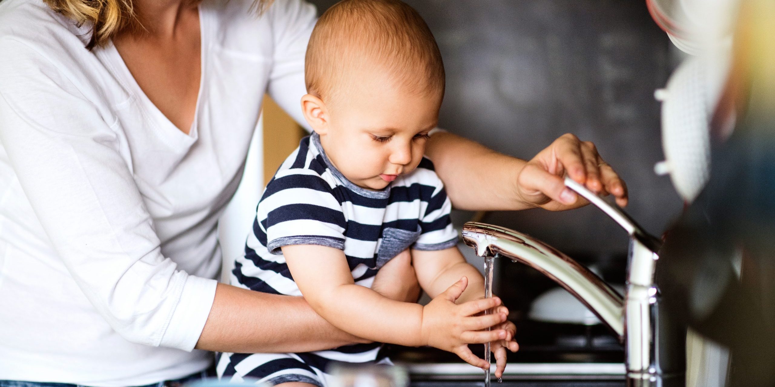 a woman and baby washing hands at a sink
